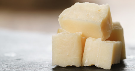 Closeup   of pieces of hard parmesan cheese on slate board