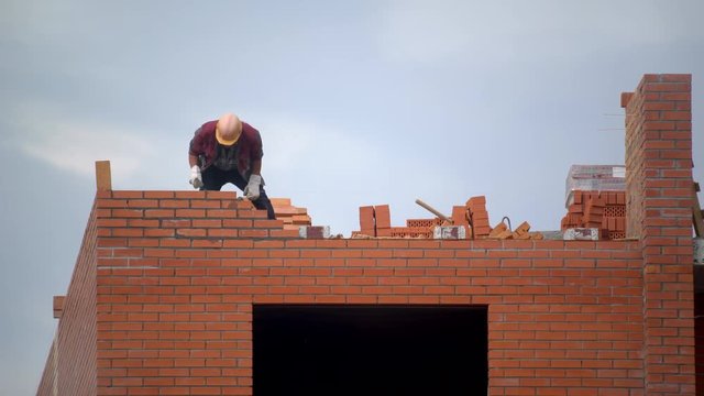 worker builds wall of bricks. builder on building making bricklaying. builder at construction site makes brickwork. brick construction site building. builder at construction site makes brickwork 4 K