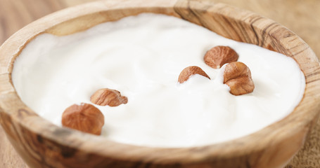 Closeup   of homemade yogurt with hazelnuts in wood bowl on wooden table