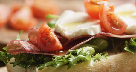 Closeup   of open sandwich with prosciutto, mozzarella and tomatoes on kitchen table