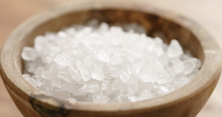 Closeup   of coarse sea salt in wooden bowl on table