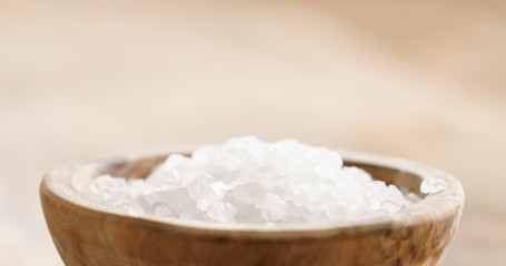 Fototapeta na wymiar Closeup of coarse sea salt in wooden bowl on table