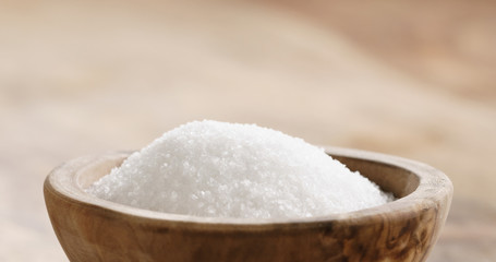 Closeup   of extra sea salt in wood bowl on wooden table