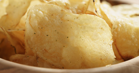 Closeup   of potato chips with herbs in wood bowl