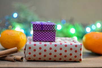 Christmas gifts in boxes, spruce branches, tangerines and Christmas lights. Christmas garland on the background. Festive mood.