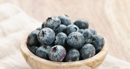 Closeup   of fresh blueberries in wood bowl on table