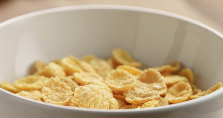 Closeup   of dry corn flakes for breakfast in bowl on table