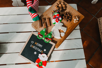 .Christmas still life consisting of typical sweets on a wooden board and a blackboard that says...