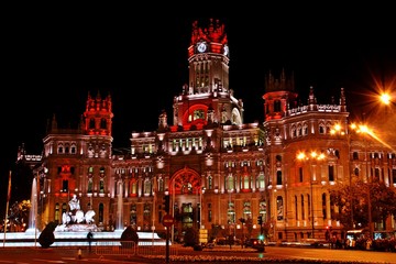 Fototapeta na wymiar Palacio de Cibeles o Palacio de las comunicaciones y Fuente de Cibeles en Madrid. Iluminadas de noche en Navidad.