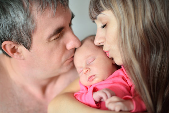 Mom and Dad kiss newborn girl