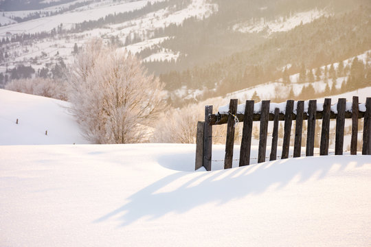 wooden fence in snow and morning sunlight. beautiful winter countryside background