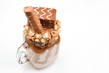 Chocolate extreme milkshake with brownie cake, chocolate paste and sweets. Crazy freakshake food trend. Copy space