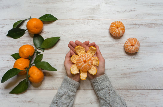 Hands peeled mandarins on a wooden table. Top view. 
