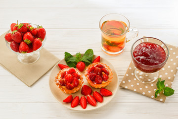 Tea drinking with tartlets and cakes with strawberries