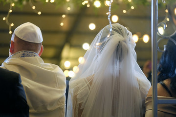 Groom with the bride on a hupa of the Jewish wedding. Rear view.