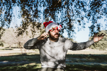 .Young man wearing santa claus costume arguing over his smartphone. Very angry with Christmas time. Lifestyle.