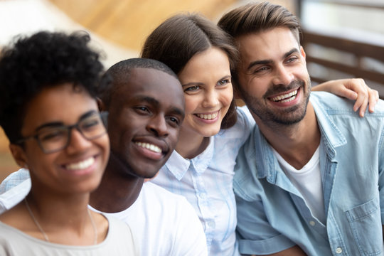 Happy multiethnic friends posing for photo together close up, excited smiling people making picture, colleagues, student in cafe embracing, having fun together, multiracial friendship concept