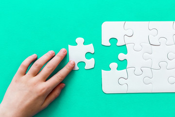 Jigsaw Puzzle with missing piece on mint background Top view People hand