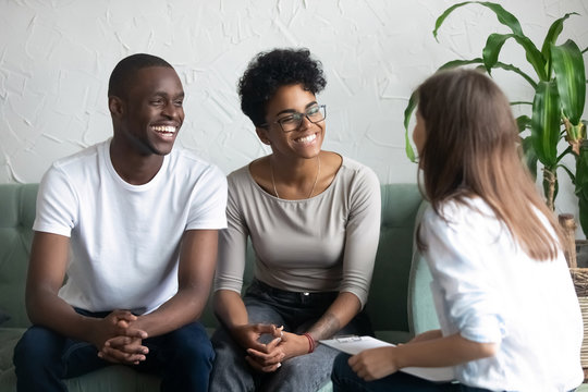 Happy African American couple at successful visit psychologist, smiling wife and husband sitting together on couch after good family therapy session, satisfied clients, help spouses solve problem