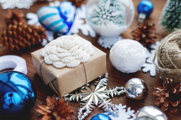 Christmas and New Year background with presents, ribbons, balls and different blue decorations on wooden background. Gift packed in craft paper with hand made crochet flower.