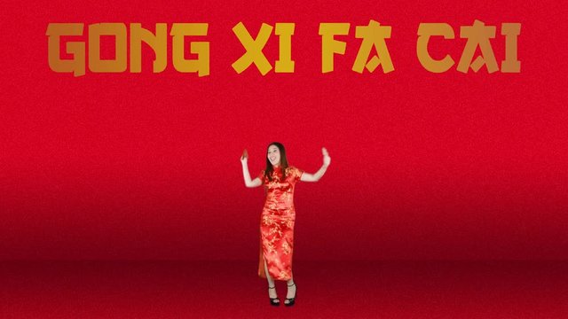 Joyful pretty Asian woman celebrating Chinese New Year while wearing red cheongsam clothes and dancing with Gong Xi Fa Cai text background. Shot in 4k resolution