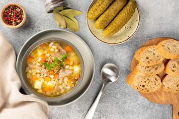 Rassolnik - Traditional Russian soup with pickled cucmbers, pearl barley, meat, pickles, carrots and potatoes  on light background. Top view
