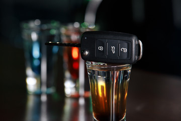 Drinking and driving concept. Car key on a wooden table, pub background