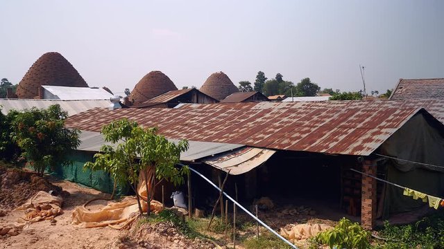 View of the local brickyard with chimneys of the bricks kilns as backdrop