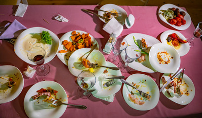 Top view of dirty plates and glasses after a meal on the restaurant table. The leftover food on dirty dishes after dinner.