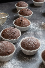 Fresh muffins with sugar icing on a wooden black table.