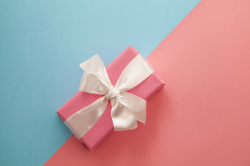 Festive pink and blue background. Gift with satin bow on coral background. Christmas. Wedding. Birthday. Happy woman's day. Mothers Day. Valentine's Day. Flat lay, top view.