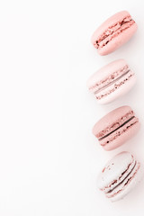 The vertical row of pastel macaroons on the light background. Copy space.