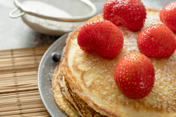 Pancakes with strawberries on a plate. Sweet breakfast or snack.