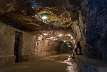 Old long damp tunnel in the catacomb with lighting