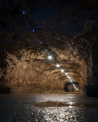 Old long damp tunnel in the catacomb with lighting