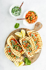 vegetarian snack of tacos with chickpea curry and sour cream sauce with parsley, spinach, green...