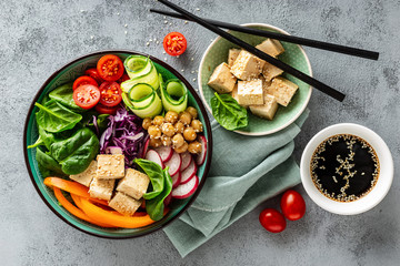Buddha bowl salad with chickpeas, sweet pepper, tomato, cucumber, red cabbage kale, fresh radish, spinach leaves and tofu cheese, healthy balanced clean eating concept, top view, flat lay.