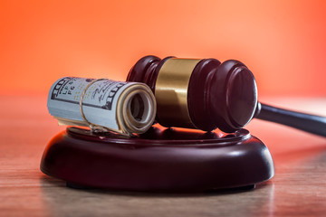Judge's gavel with dollars in roll and golden coins