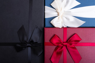 Red, black and blue gift boxes and red ribbon background