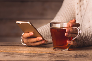 a cup of black tea and a telephone in the hands of a girl