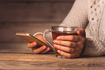 a cup of black tea and a telephone in the hands of a girl