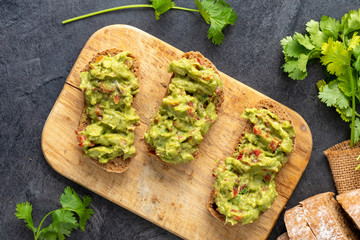 Fresh bread with Mexican homemade guacamole on a black table.