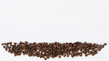 Part of frame roasted coffee beans down on white wooden background, top view. Copy space, free place for text