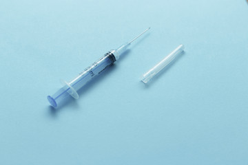 Medical syringe with cap close-up on a blue background. Medicine concept