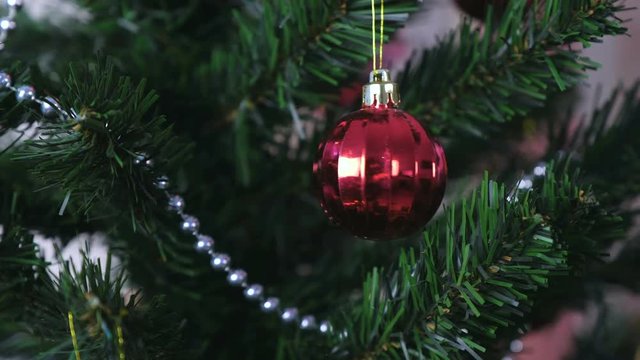 Spinning red shiny ball on Christmas tree.