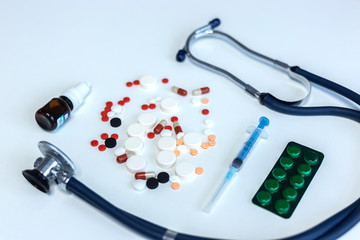 Closeup syringe, medicines and pills, stethoscope on white background.