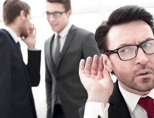 close up.businessman eavesdropping on conversation between colleagues