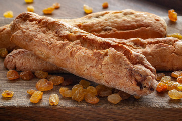 Raisin cookies and rolled raisins on a wooden board.