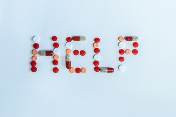 Colored pills on white background. Inscription help closeup..