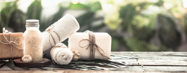Spa handmade soap with white towels and sea salt, composition on tropical leaves, wooden background